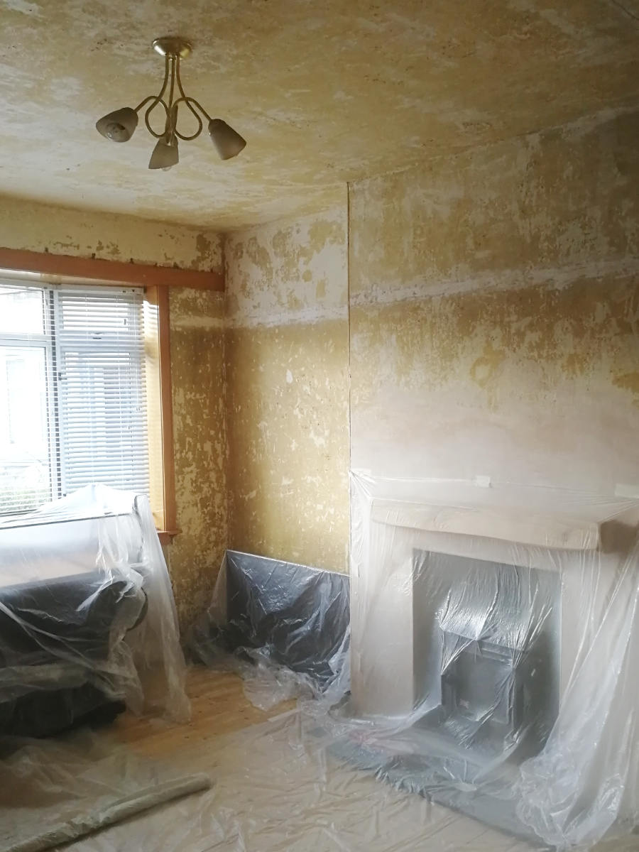 Living room prepared for plastering with protectice sheets coveribg floor and furniture